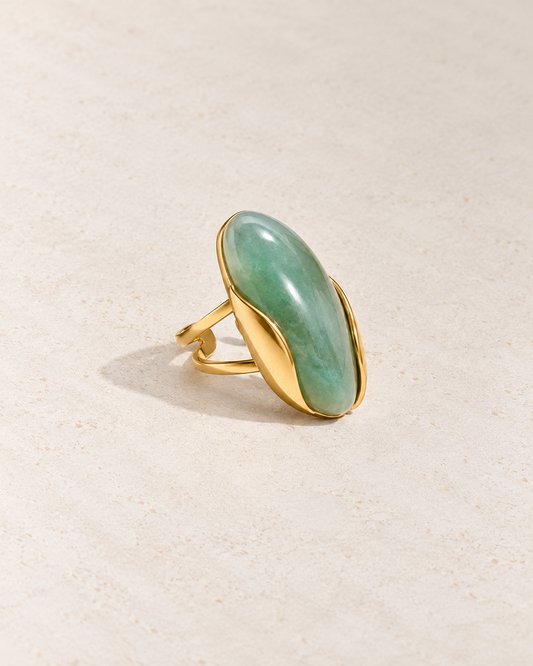 Anillo Isabella con piedra verde sobre cemento blanco