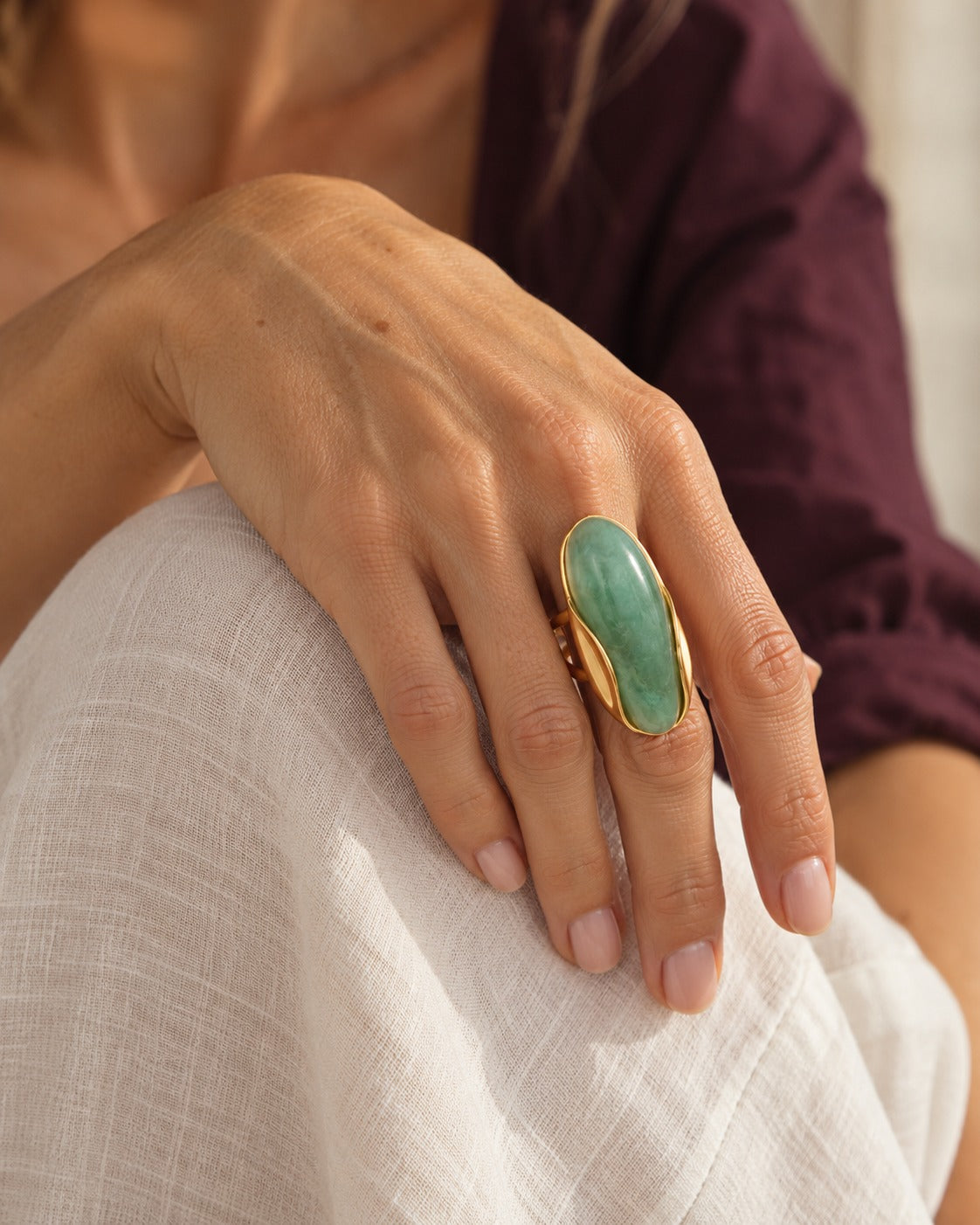 Anillo Isabella dorado con piedra verde puesto en mano de modelo